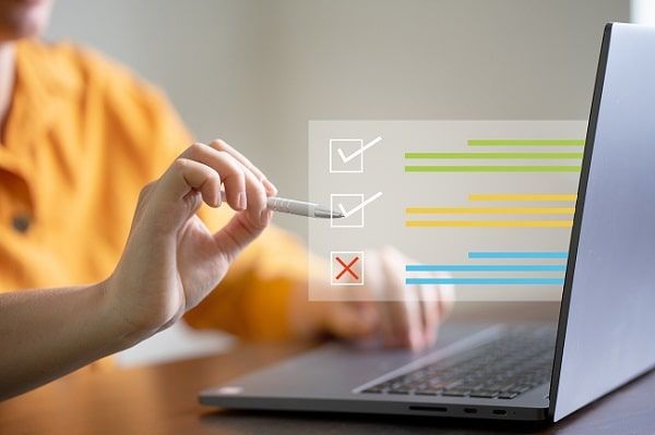 En person fyller i en digital enkät med kryssrutor på en bärbar dator.