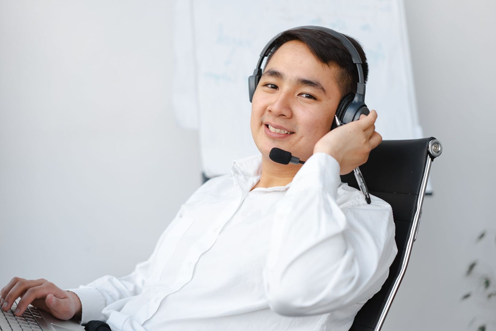 En leende kundtjänstmedarbetare med headset vid datorn.