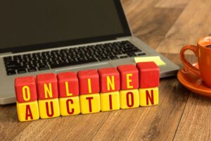 Träklossar med texten ONLINE AUCTION framför en bärbar dator.