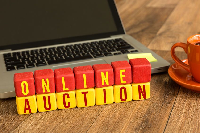 Träklossar med texten ONLINE AUCTION framför en bärbar dator.