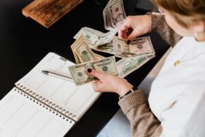 En person räknar amerikanska dollarsedlar vid ett skrivbord med en planeringskalender.