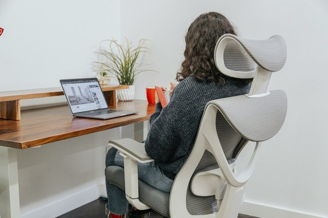 Person sitter vid laptop i ergonomisk kontorsstol vid ett skrivbord